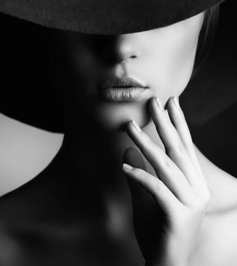 Black and white image of a woman wearing a big black hat that's covering her eyes