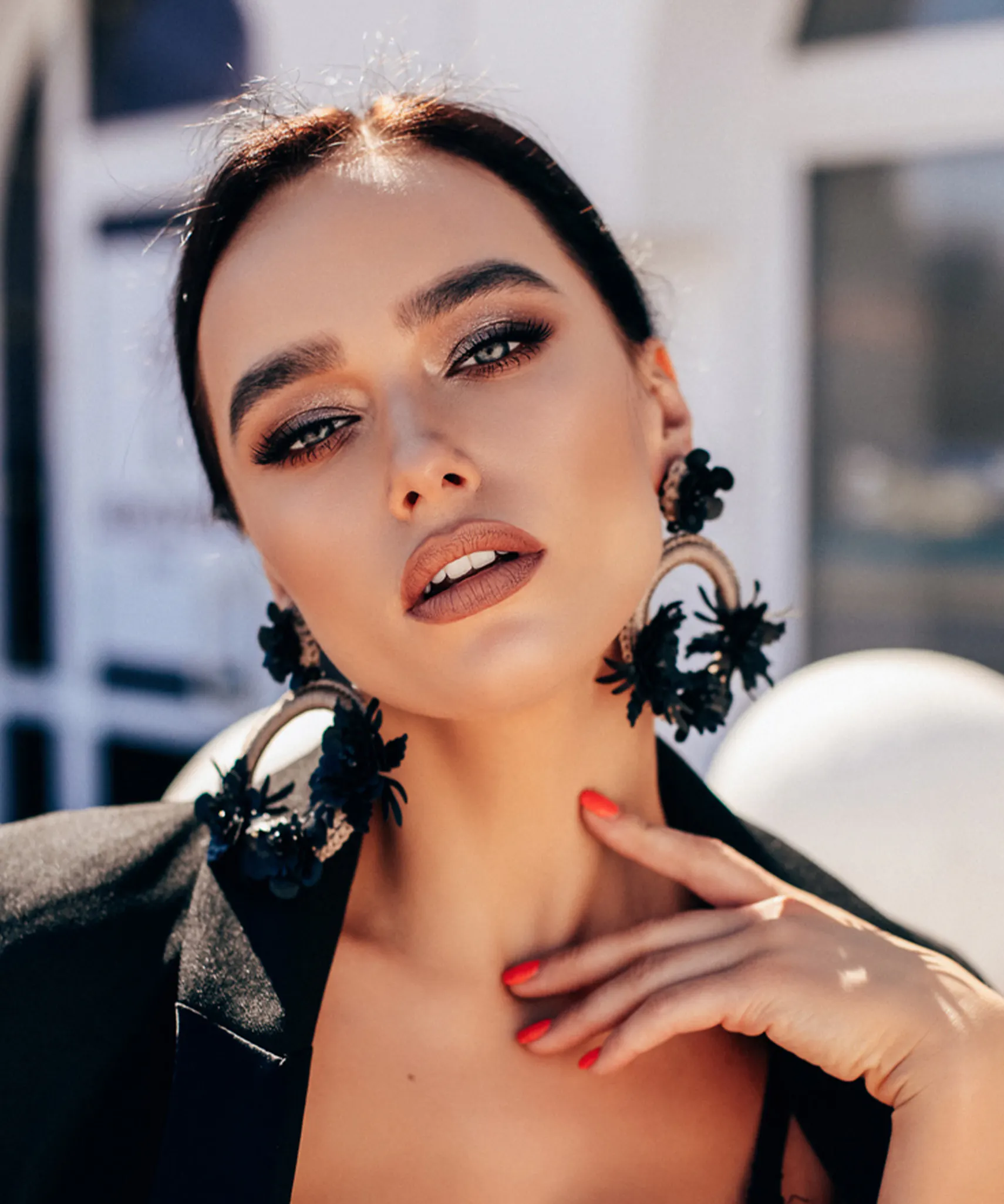 woman with black jacket and red nails posing for a picture